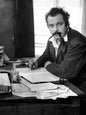 Photo Georges Brassens écrivant à son bureau, une pipe à la bouche - 15 x 20