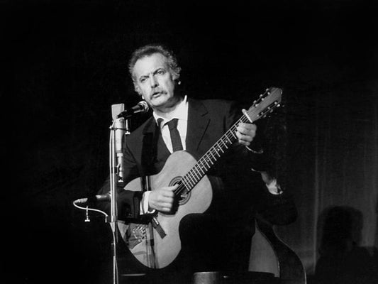 Photo Georges Brassens jouant de la guitare en chantant sur scène - 15 x 20