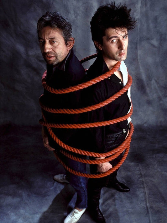 Photo Serge Gainsbourg & Alain Bashung dos à dos par une corde en 1982 - 15 x 20
