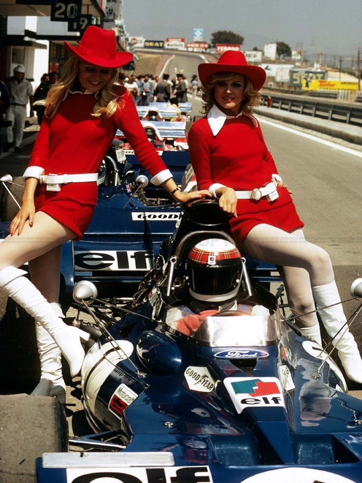 Photo Jackie Stewart avec 2 Grid Girls - paddock F1 années 70 - Couleur - 15x20
