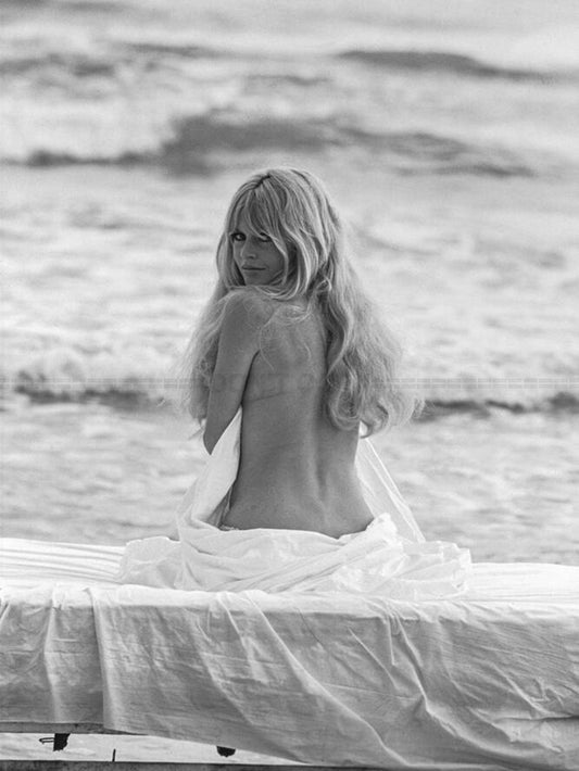 Photo Brigitte Bardot de dos, assise sur un lit face à la mer en 1965 - 15x20