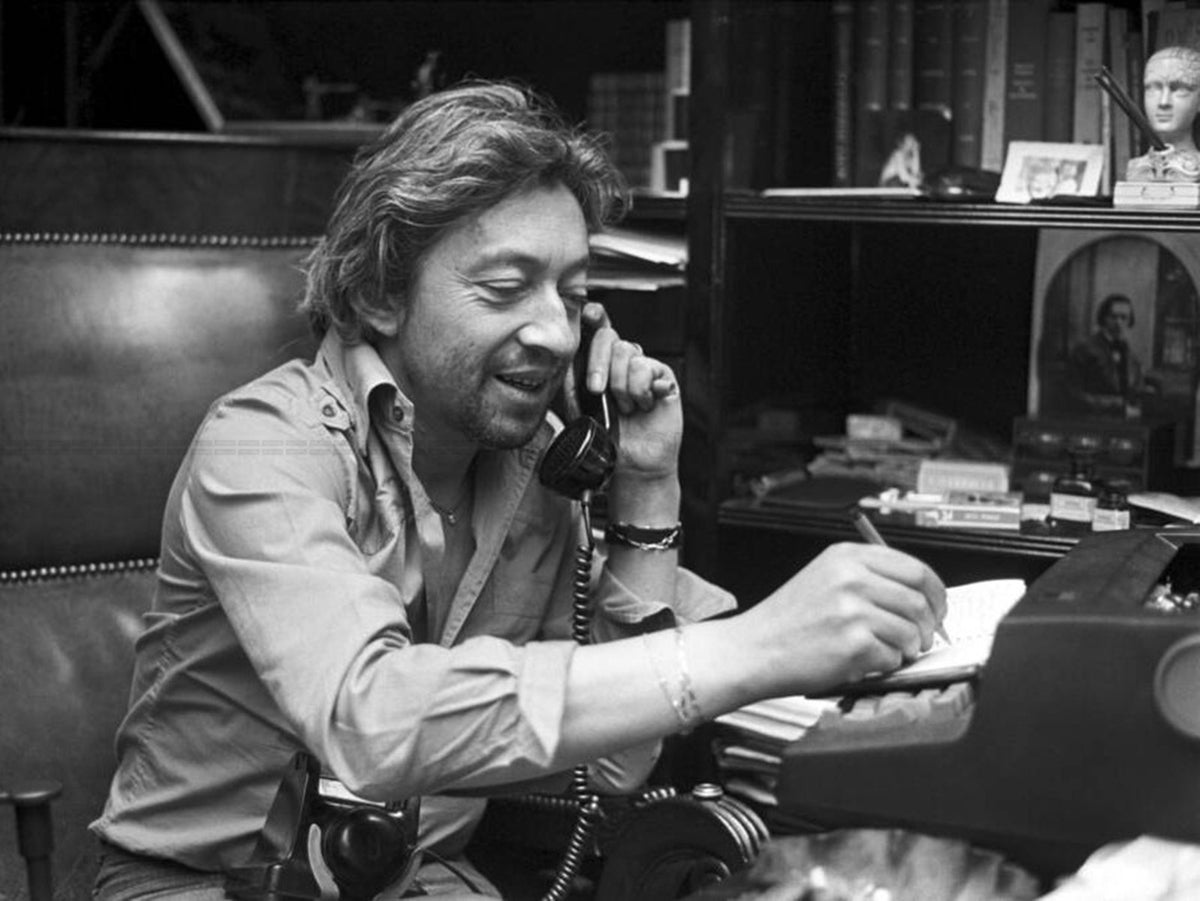 Photo Serge Gainsbourg au téléphone et écrivant chez lui à Paris, 1977 - 15 x 20